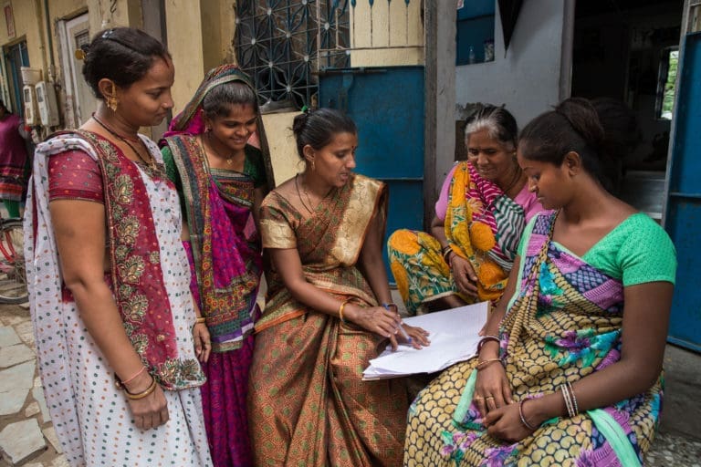 women gathered outside their homes talking.