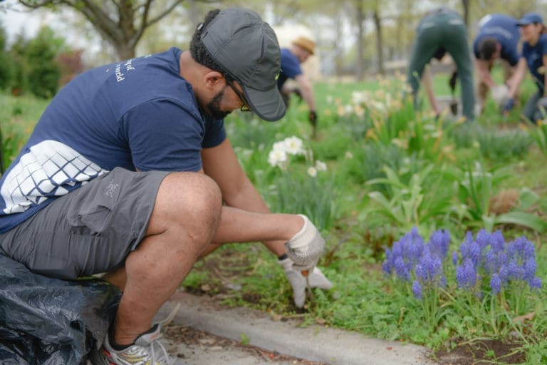 Man gardening with others gardening behind him.