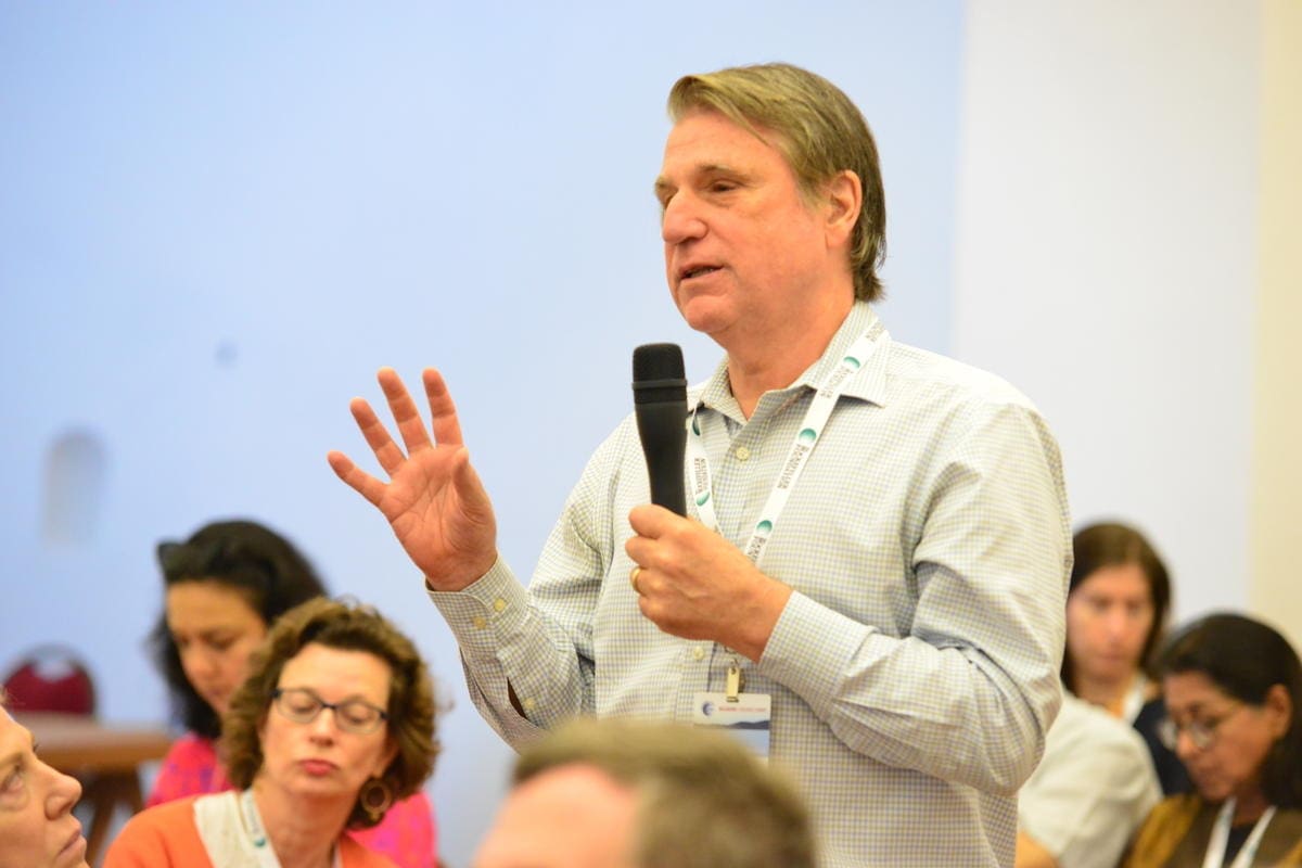Man raising his hand and holding a microphone.