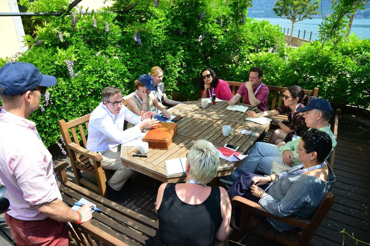 men and women sitting around a table talking to each other.