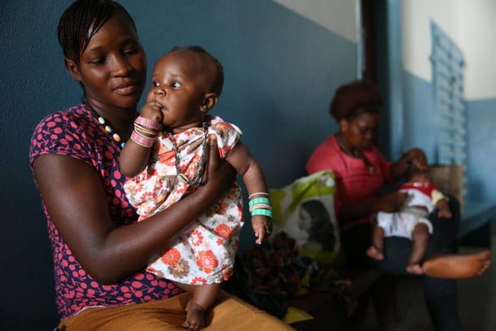 woman sitting and holding a child in her arms.