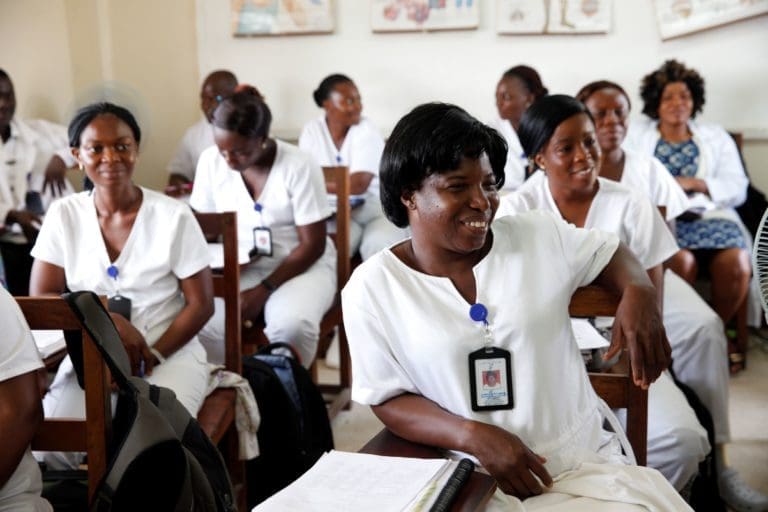 women who appear to be healthcare workers sitting at desks.