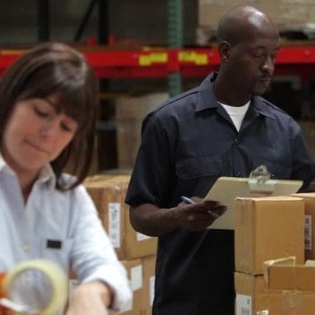 Man and a woman working in a warehouse.