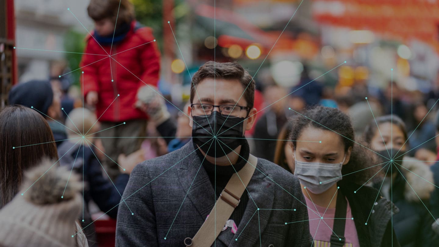 People wearing masks walking down the street.