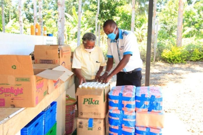 two males standing over a box of bottled beverage