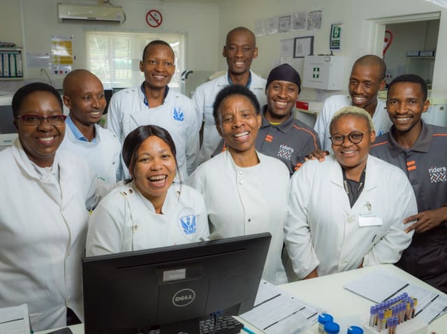 Laboratory Staff and couriers for Riders for Health smiling.