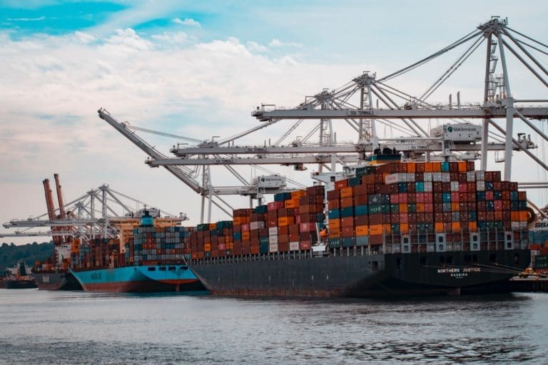 Cargo ships docked by land.