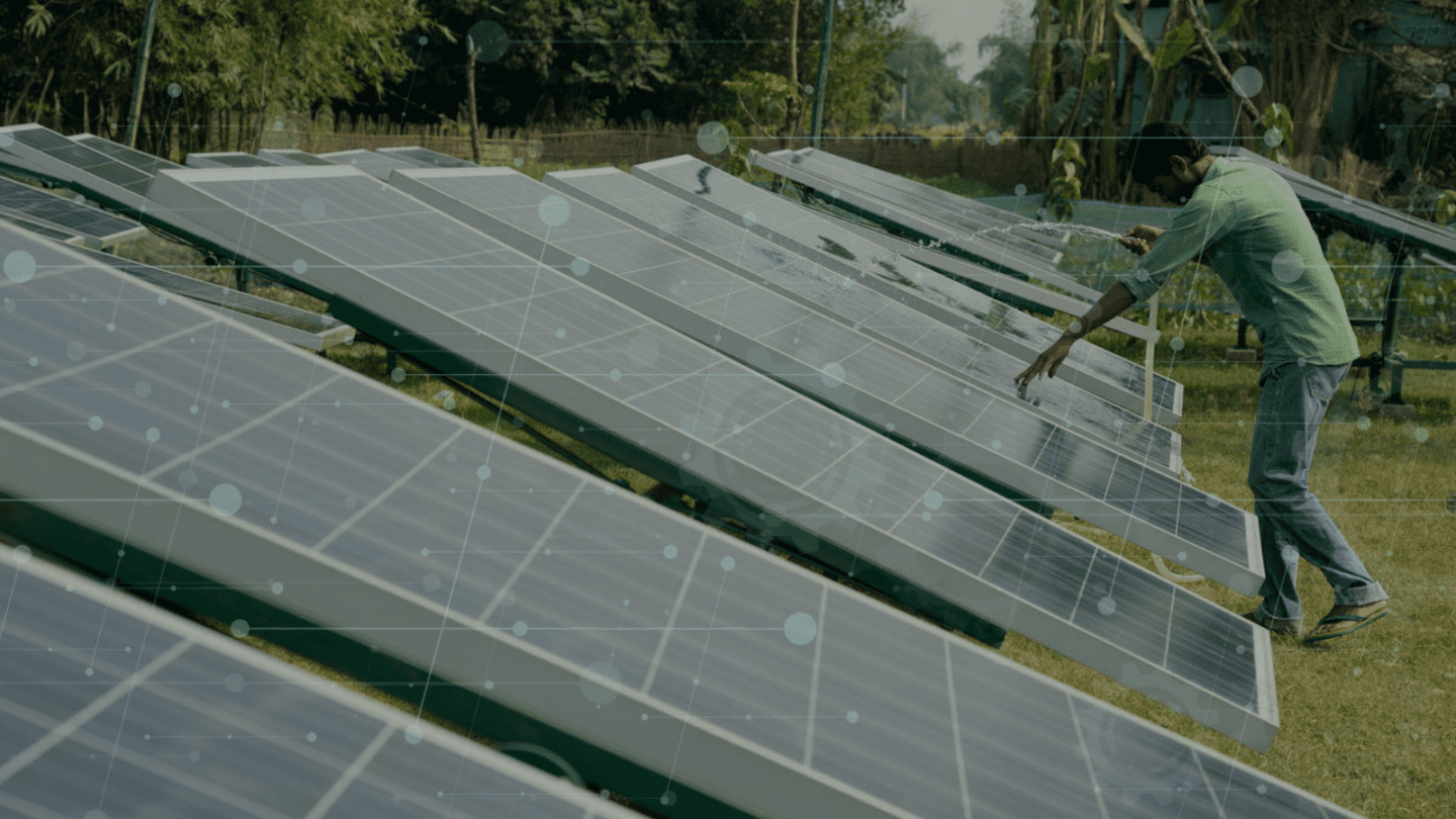 Man leaning over and pouring water from a hose to clean solar panels.