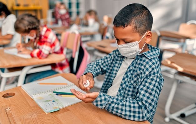 young boy spraying sanitizer on his hands
