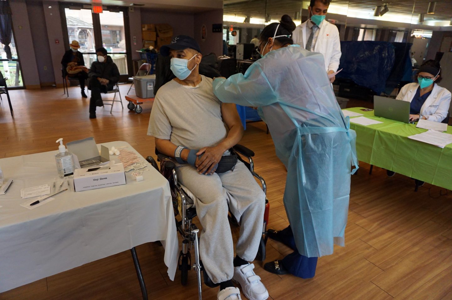 health worker giving a man receiving a vaccine shot in the arm.