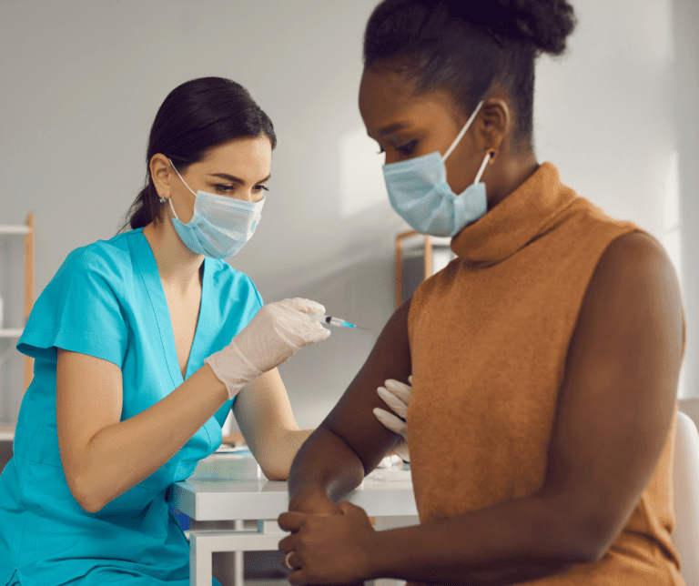 Image is of a woman receiving a vaccine shot.