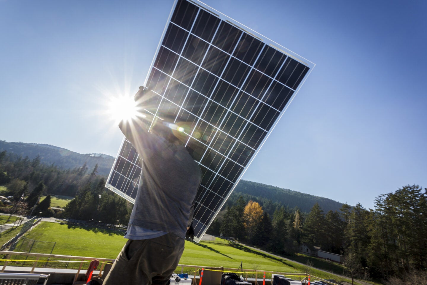 Image is of a man holding a solar panel.