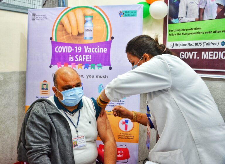 health worker giving a man the covid-19 vaccine in his arm.
