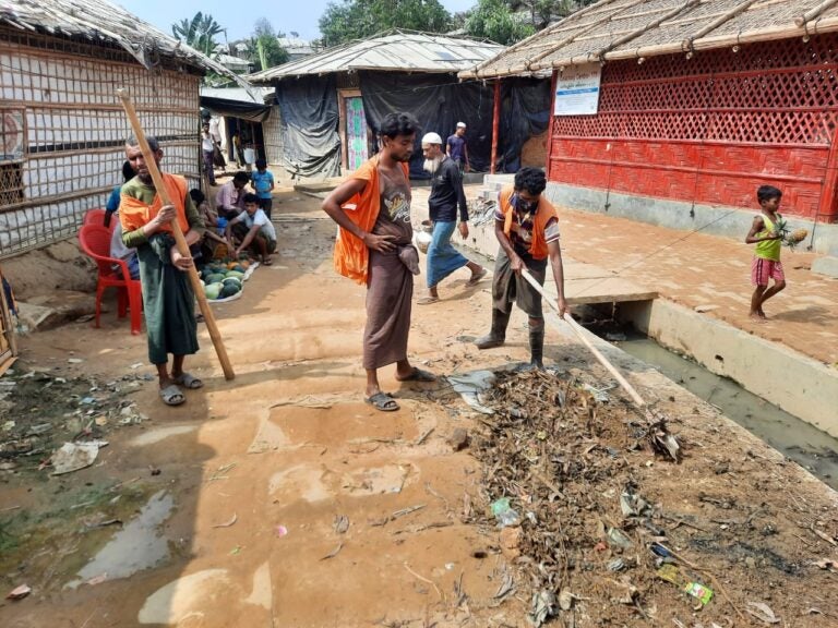 people cleaning open sewage drain