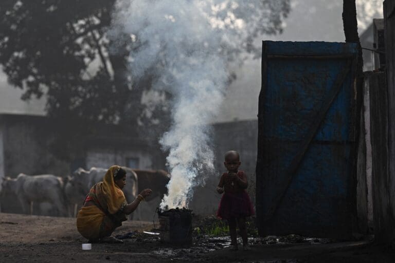 a woman and a child standing next to burning coal.