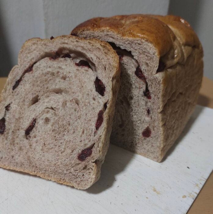 Image is of a bread loaf made with rainbow rice leaf powder,