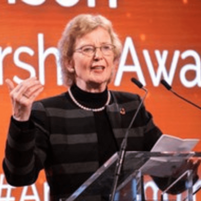 woman standing at a podium talking in a microphone.