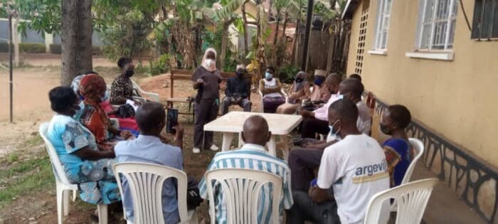 Image is of a Vaccination Champion speaking to a Community in Wakiso.