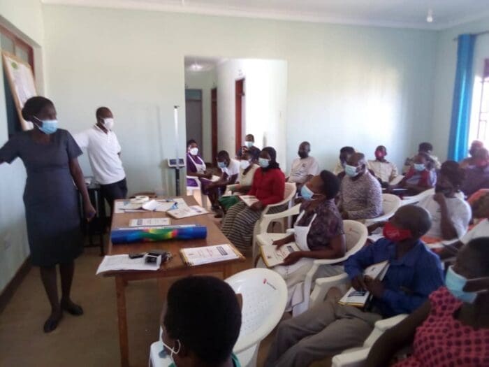 Image is of a nurse training a group of vaccination champions.