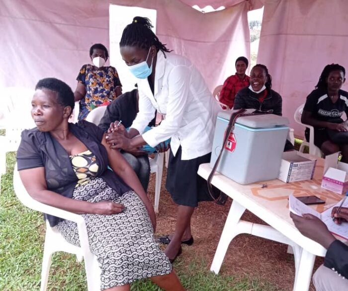 Image is of nurse Nabwiire giving a vaccine to a patient.