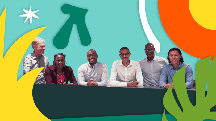 group of men and women sitting at a table with their arms crossed smiling at the camera.