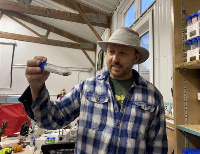 man wearing a hat holding a test tube in his hand.