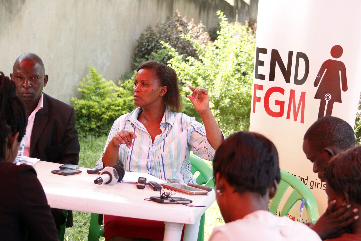 Media Science Cafe in Uganda -- group of people around a table outdoors discussing female genital mutilation