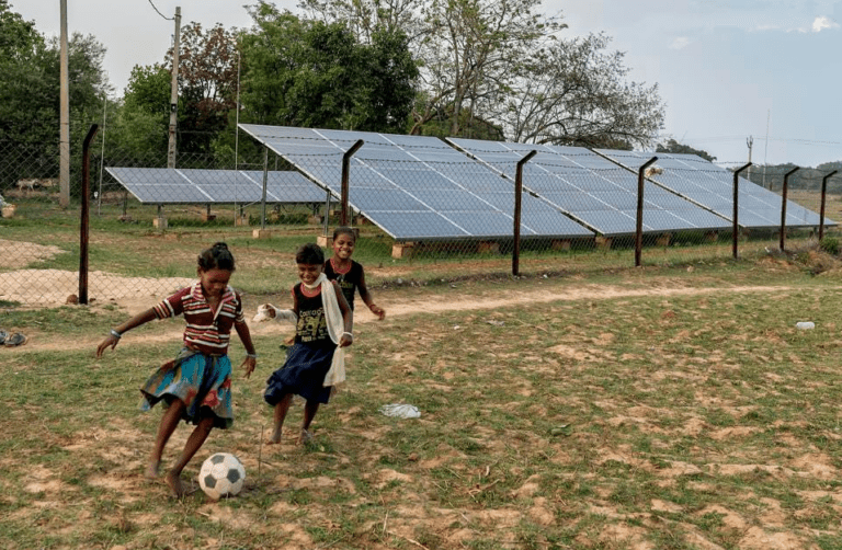 group of young girls playing soccer in front of a solar grid