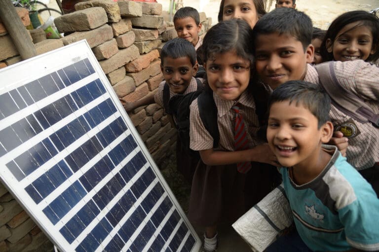 Children standing next to solar panels