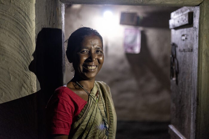 Woman benefitting from light from solar-powered mini-grid