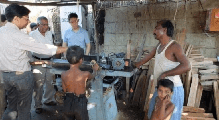 Tamesh Sharma, a carpenter in the village of Bara in Bihar, India, explains to visitors in 2013 how use of electricity improves the quality of his product and reduces time spent. (Photo Credit Zia Khan)