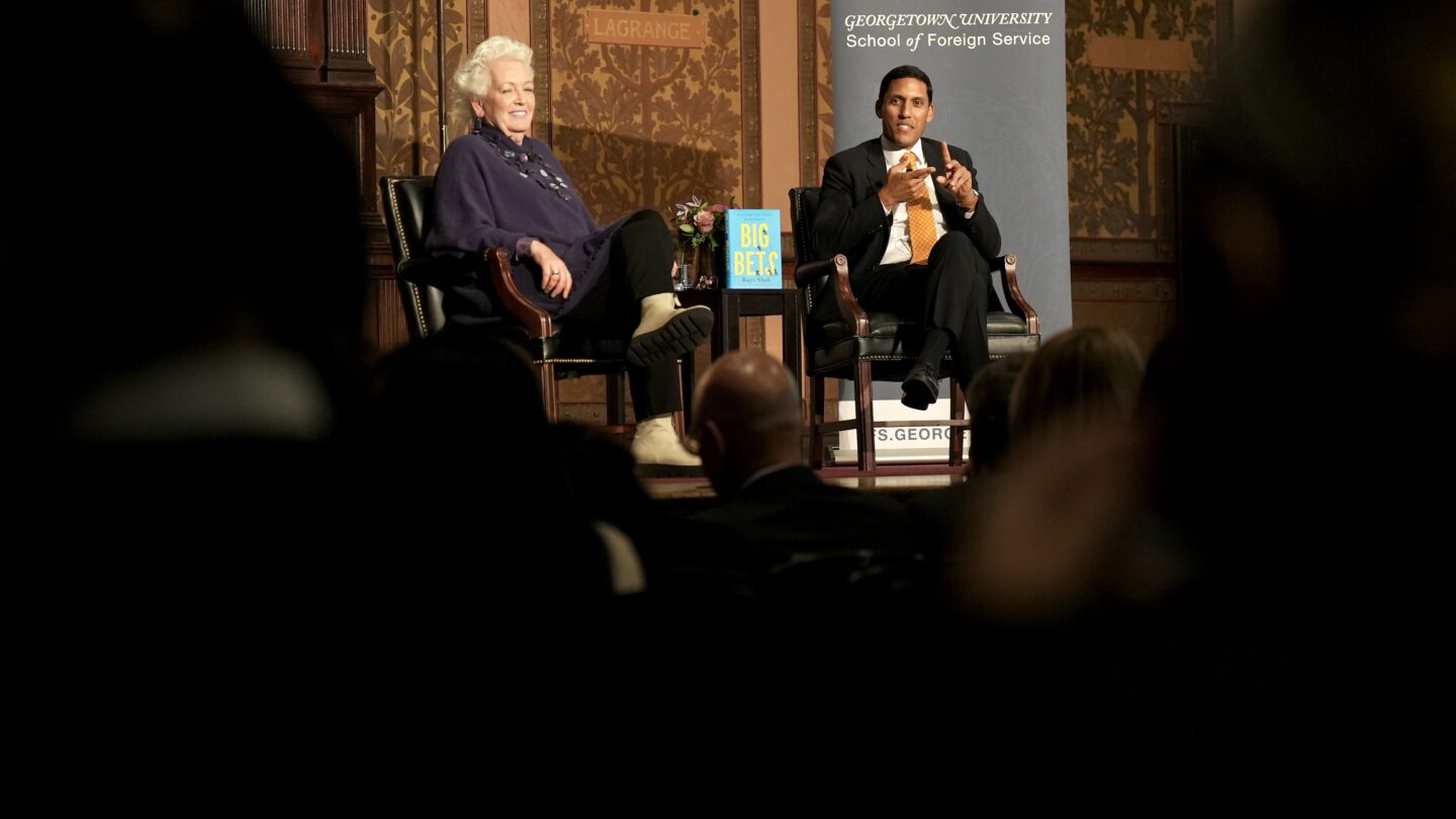 man and a woman sitting in chairs on stage talking about the new book "Big Bets" by dr. rajiv j. shah the president of the rockefeller foundation
