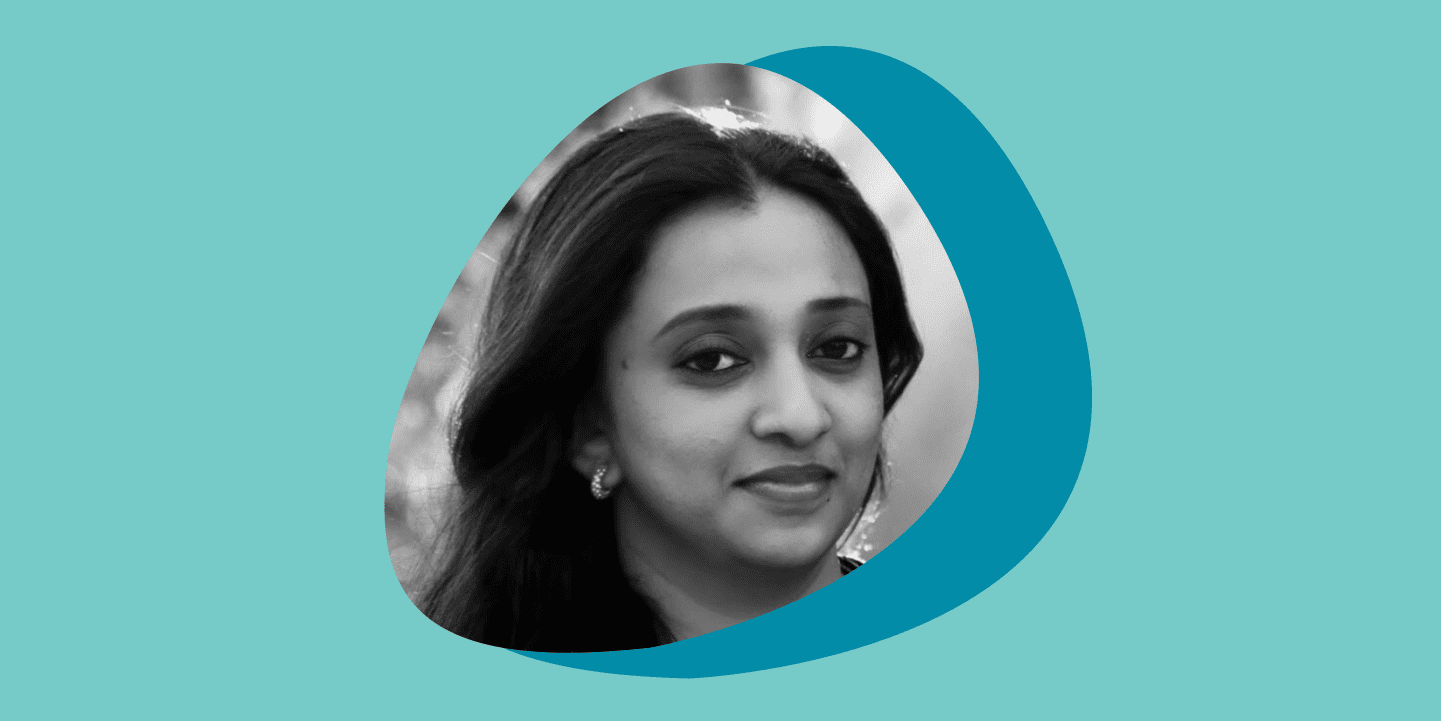 Black and white portrait photo of a woman smiling at the camera in a circular frame, set against overlapping teal and turquoise circles on a light teal background