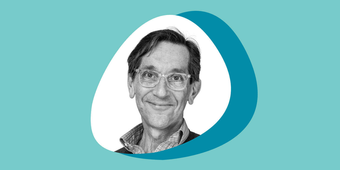 A black and white photo of a man smiling at the camera in a rounded, triangular frame, set against overlapping teal and turquoise circles on a light teal background