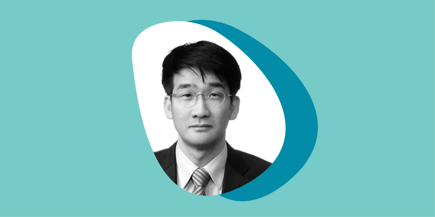 A black-and-white photo of a man looking at the camera with a neutral expression in a rounded, triangular frame, set against overlapping teal and turquoise circles on a light teal background