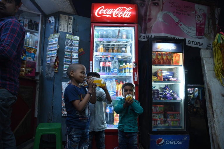 Children drinking soda from a mini-grid powered shop in Derni, Bihar.