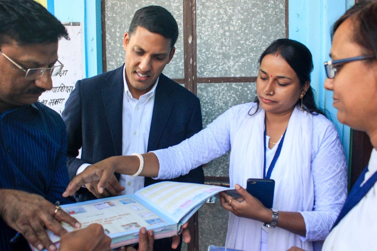 two men and two women all standing and looking at a book together.