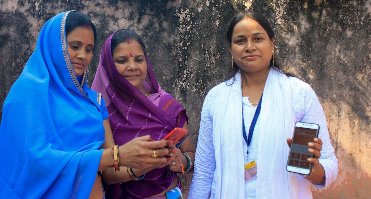 three women standing and holding their phones up.