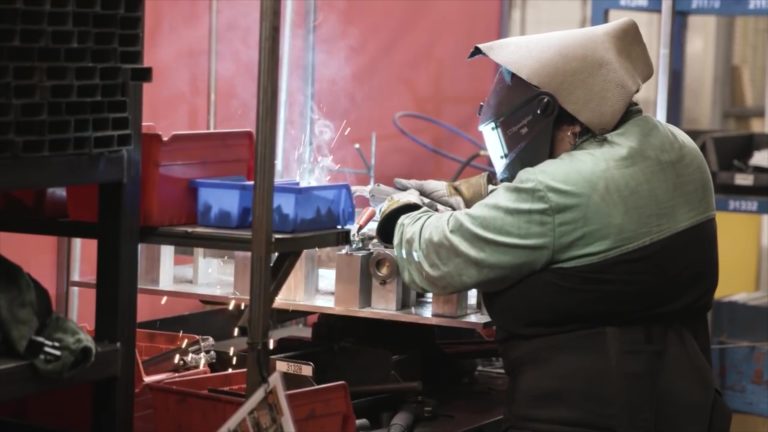 man wearing a facemask working on a machine.