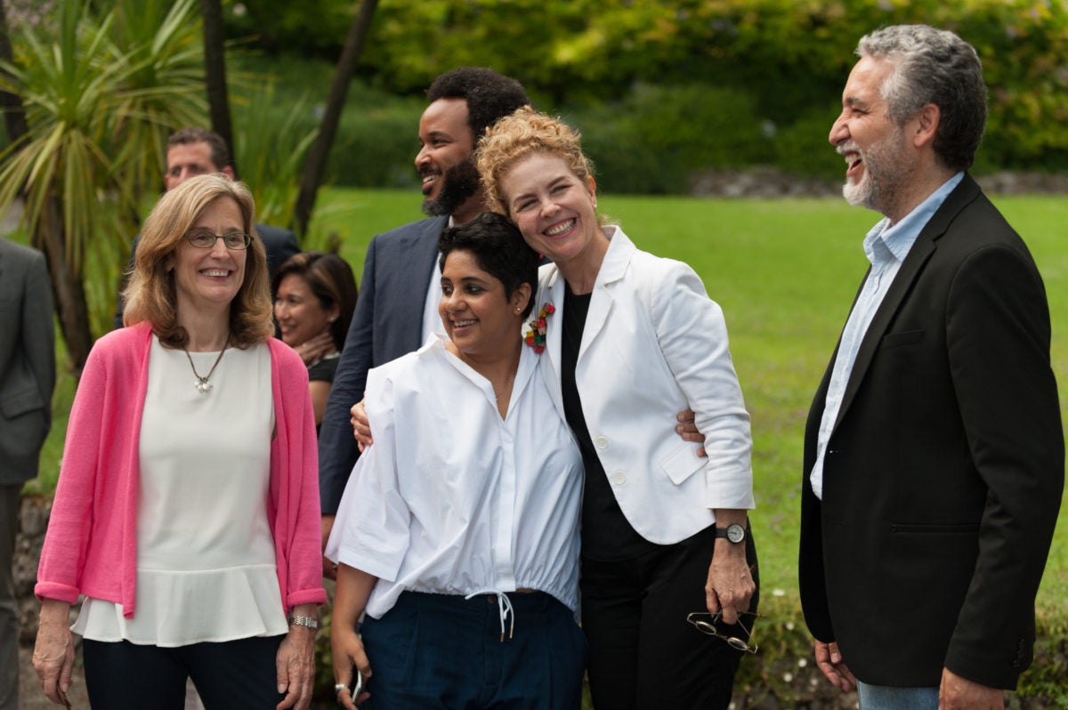 men and women standing around with a woman putting her arm around another woman.