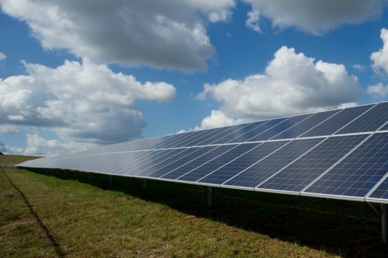 solar panel power grid in a field with clouds in the sky.