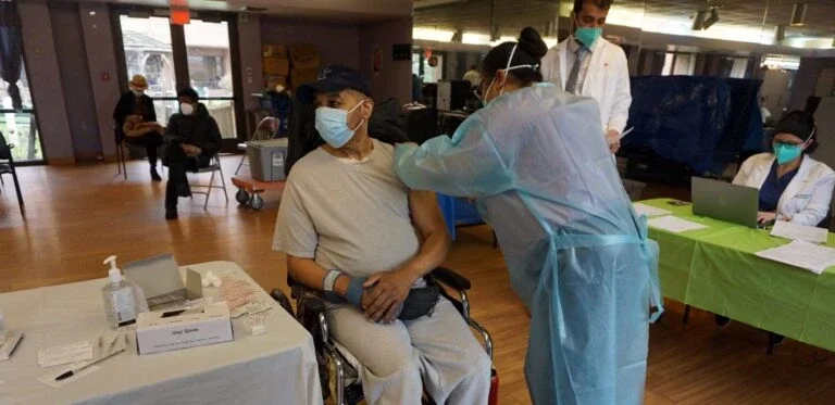 health worker giving a man receiving a vaccine shot in the arm.