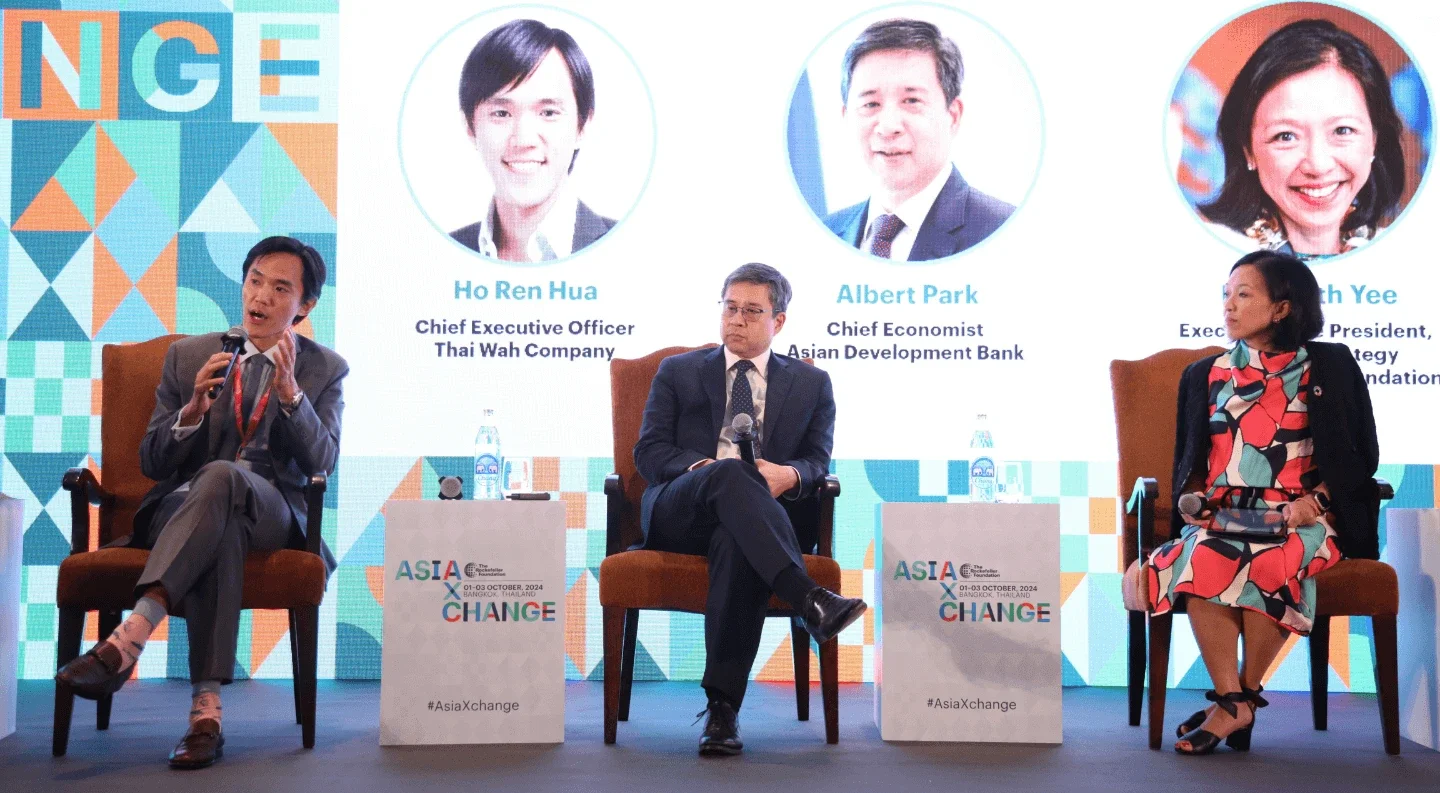 a panel discussion featuring four people sitting on chairs, actively participating and exchanging ideas in front of an audience.