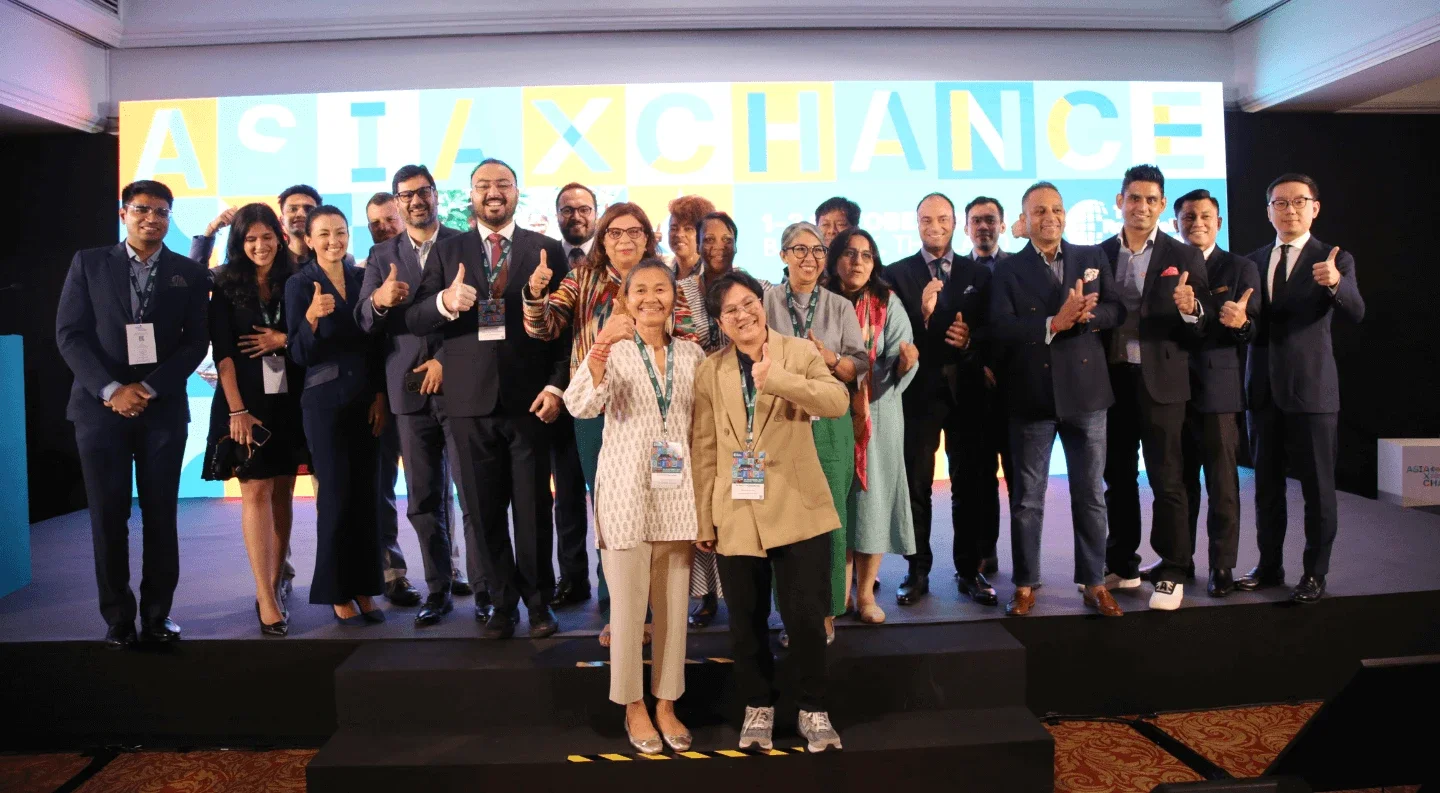 a group of people on stage smiling and giving thumbs up, celebrating a successful event or achievement.