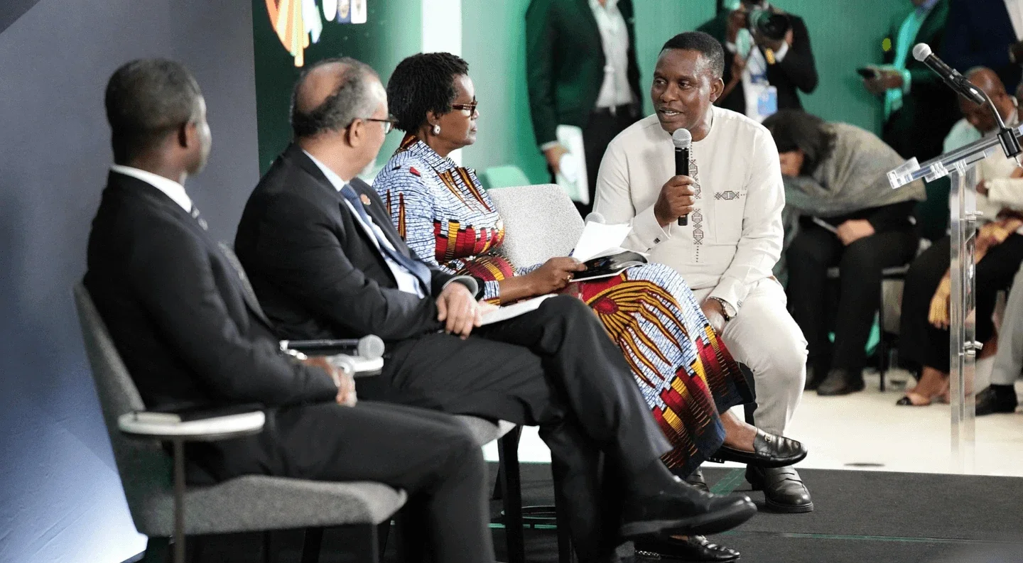 panelists speak during a Rockefeller Foundation UNGA 2025 session, with one man holding a microphone while engaging in discussion alongside fellow leaders seated on stage.