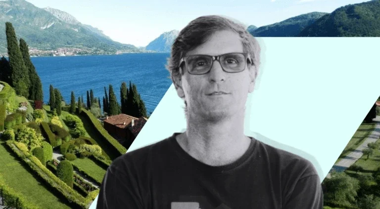 Black-and-white portrait of a man wearing glasses over a scenic background of the Bellagio Center overlooking Lake Como, Italy